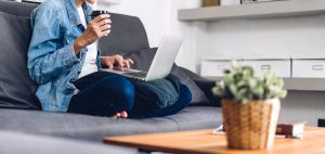 A person sits on a couch while typing on their laptop. Learn more about how online therapy in Greenwood Village, CO can offer support from the comfort of home. Contact an online therapist in Colorado to learn more about online anxiety treatment in Greenwood Village, CO and more. 
