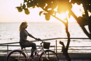 caucasian woman riding her bike while out at the sunset. Learn coping skills from an online therapist in Colorado. Online therapy in Colorado is here for you. 