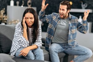 Couple sitting on the couch and male is yelling at the female . online therapy in colorado can help you manage your anger. therapist for anger issues near Greenwood village, CO can support you. 